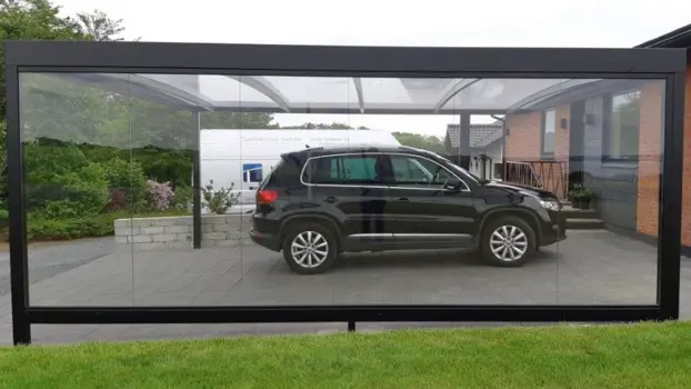 Sortlakeret UNA carport med glas som sidebeklædning. Et flot kig til bilen